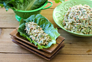 Tuna Salad in a romaine lettuce leaf in front of a bowl of more tuna salad