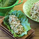stack of wood plates with large romaine lettuce leaf filled with twisted tuna salad