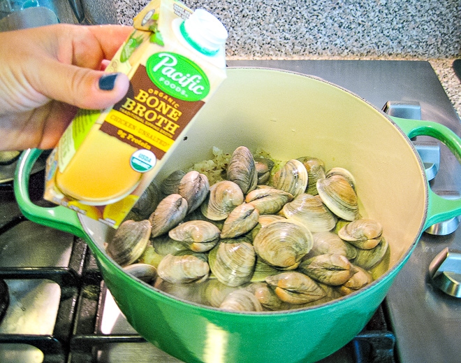 pouring broth into pot with littleneck clams