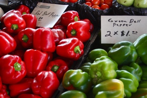 red and green bell peppers for sale in a grocery store bin