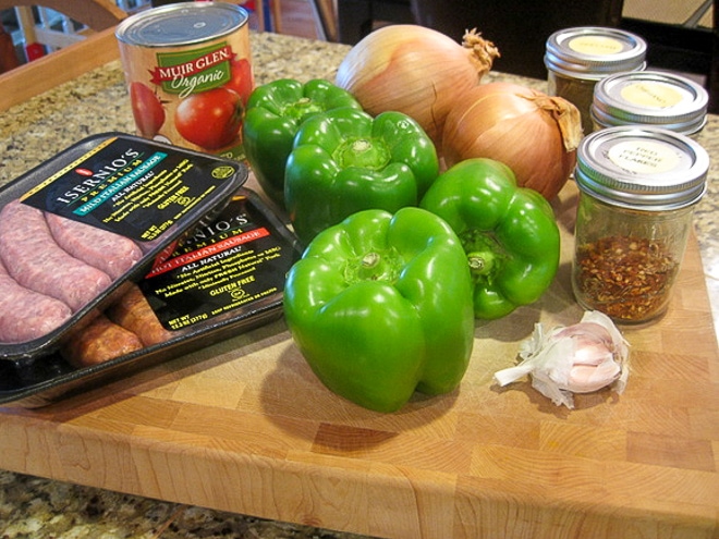 ingredients to make crockpot sausage and peppers on a wood cutting board