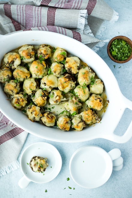 plate of stuffed mushrooms with white serving plates and chopped parsley