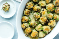 close up of baked stuffed mushrooms in a white baking dish
