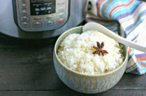 bowl of cooked instant pot rice with star anise on top in front of instant pot