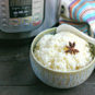 bowl of cooked instant pot rice with star anise on top in front of instant pot