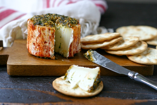 Marinated goat cheese appetizer with crackers on a wood board