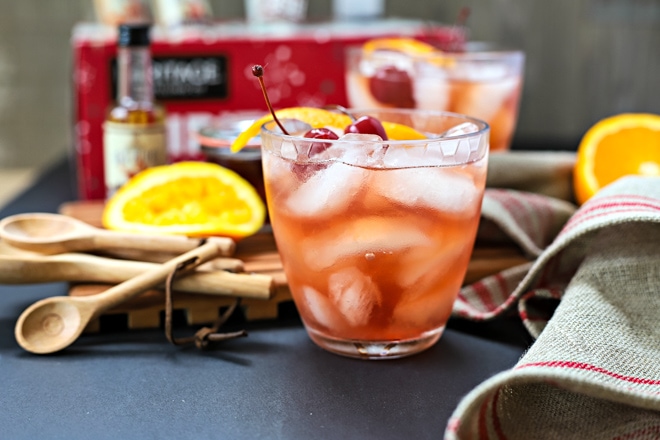 manhattan cocktail over ice with cherries and orange slices