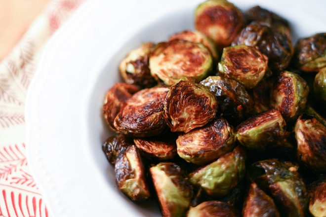 white bowl filled with crispy roasted brussels sprouts and patterned linen