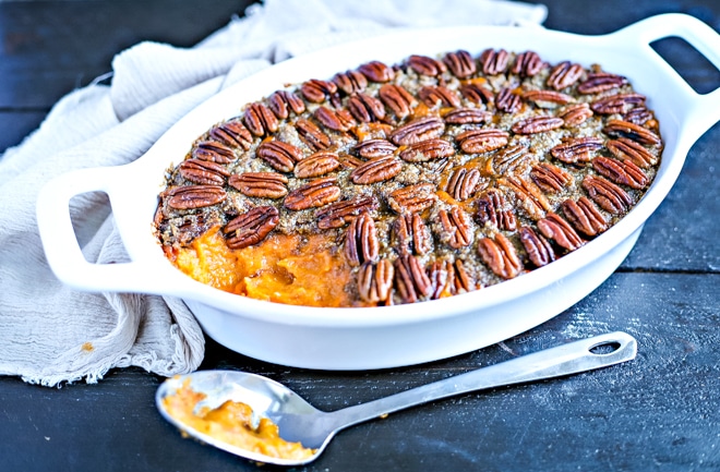 healthy sweet potato casserole topped with pecans in white baking dish