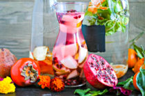glass pitchers filled with fruit infused water with cut fruit around the bottles