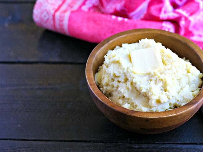 wood bowl of mashed potatoes with a pat of butter on top