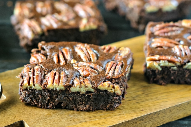 close up of one maple pecan brownie on a wood tray