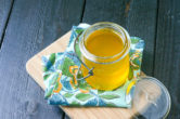 jar of ghee with a blue and yellow linen on a wood cutting board