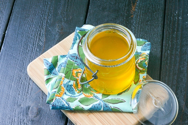 jar of ghee with a blue and yellow linen on a wood cutting board