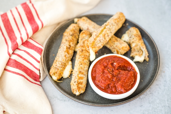 gray platter with hot mozzarella sticks and a small white dish of marinara for dipping