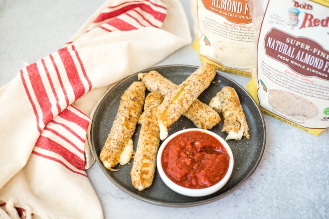 cooked mozzarella sticks with pizza sauce on a gray plate