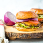 horseradish burger with sliced red onion on a wood chopping block