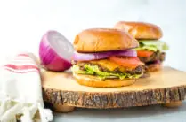 horseradish burgers with sliced onion on a wood cutting board