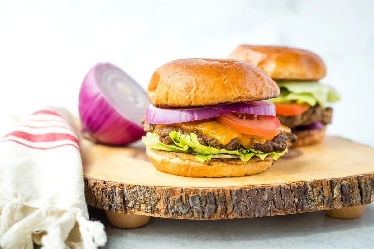 horseradish burgers with sliced onion on a wood cutting board