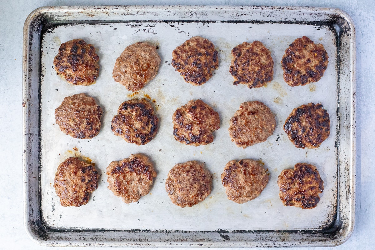 fully cooked breakfast sausage patties on a baking sheet