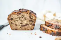 sliced banana bread loaf with stack of slices on a cutting board