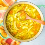 pot of bright yellow turmeric noodle soup with chicken