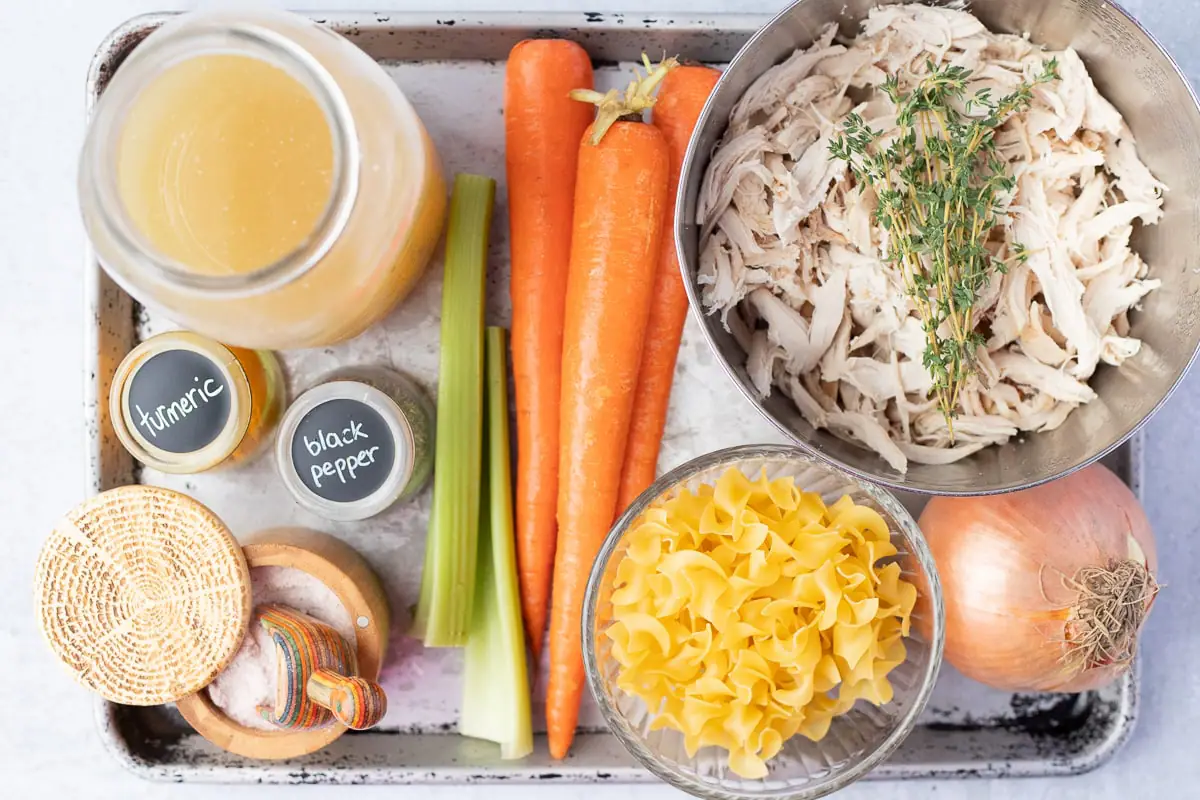 ingredients to make turmeric chicken soup on a baking sheet