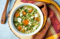 white bowl of turkey barley soup with colorful autumn linen and wood spoon