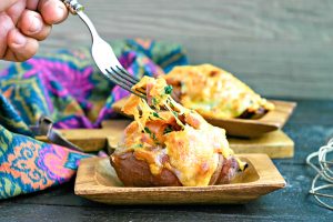 stuffed sweet potatoes on a wood dish topped with melted cheese