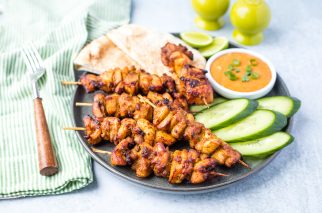 serving platter of chicken kebobs cooked in the air fryer with dipping sauce, cucumbers, and pita bread