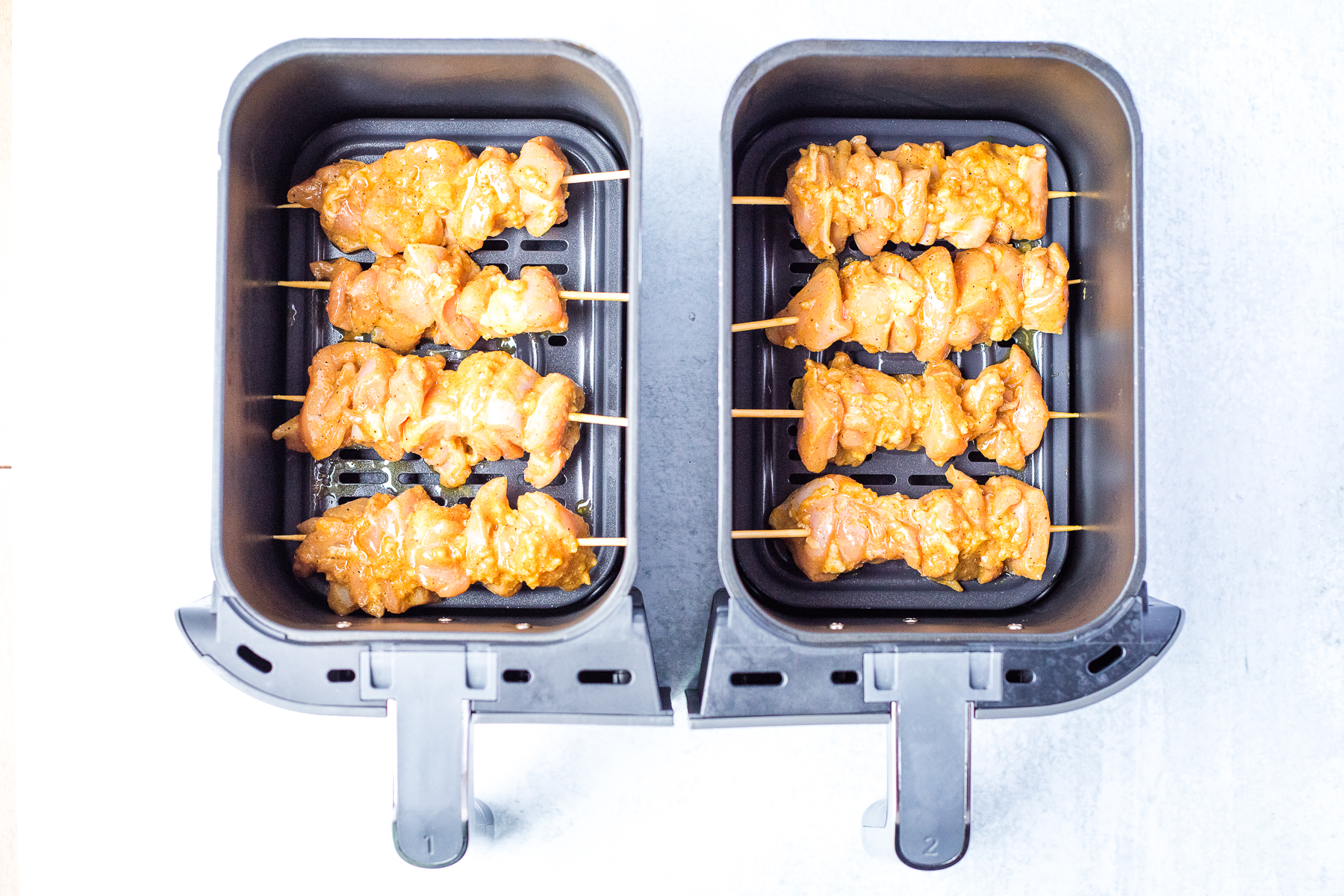 uncooked chicken kebobs arranged in an air fryer