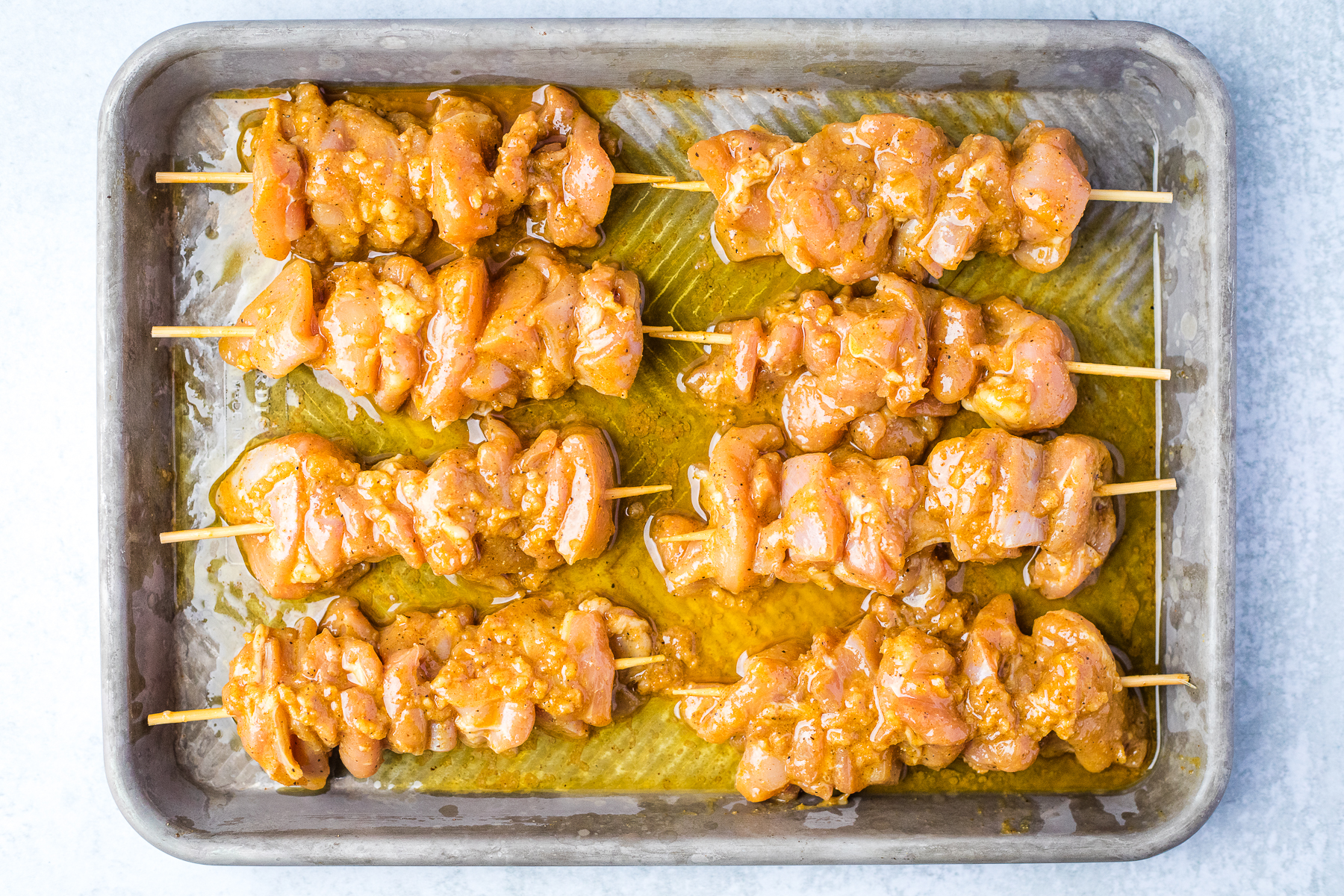miso marinated chicken on wood skewers on a baking sheet